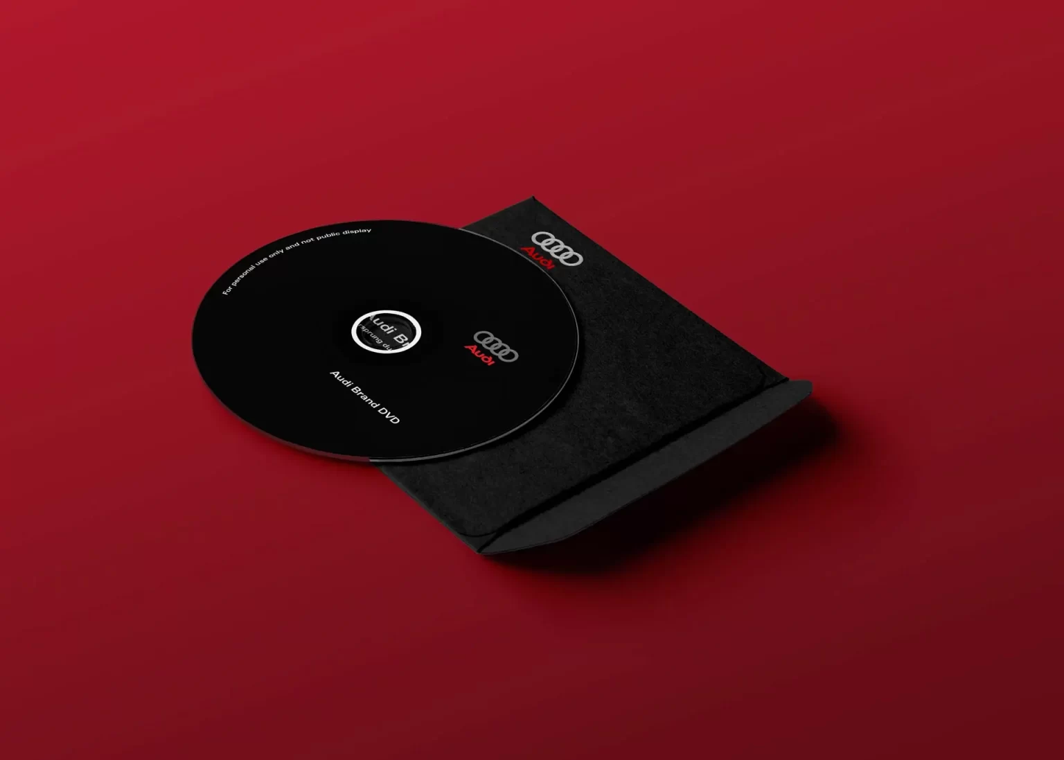 A black DVD labeled "Audi Brand DVD" is partially out of a black case on a red background.