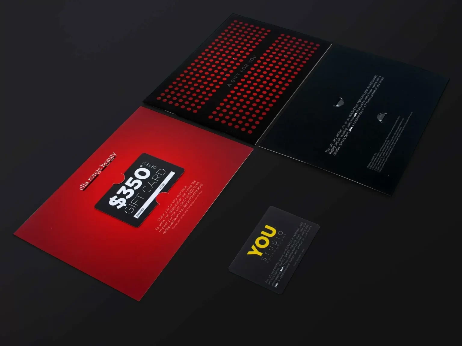 A $350 gift card and accompanying materials are laid out on a surface. The gift card is black, and the packaging is red and black with printed text.
