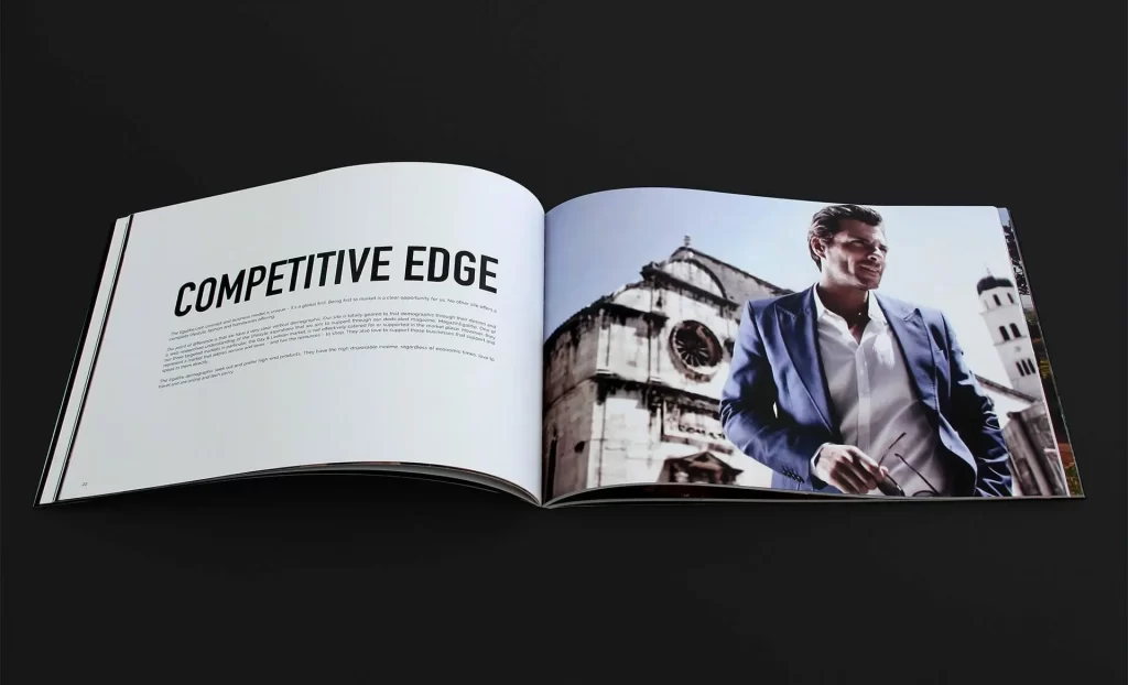 An open magazine showing a headline "Competitive Edge" on the left page and a man in a blue suit holding sunglasses in front of a European-style building on the right page.