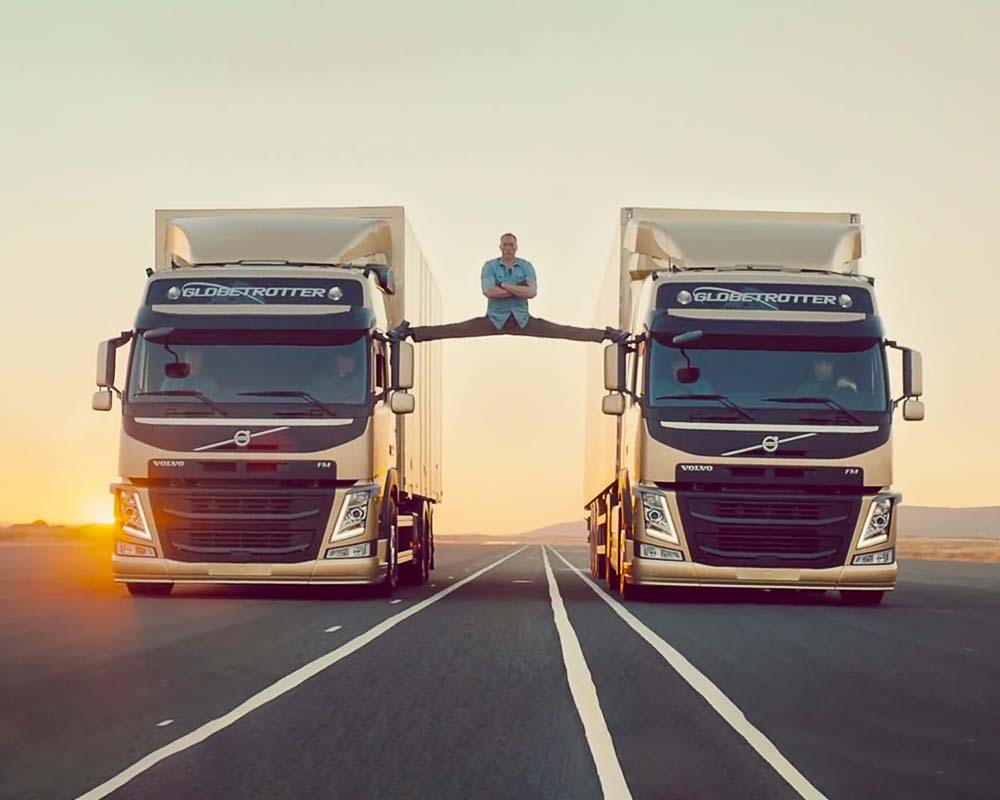 A man is standing on top of two large trucks.