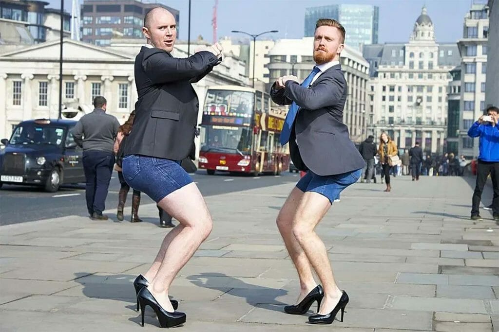 Two men in suits and shorts on a city street.