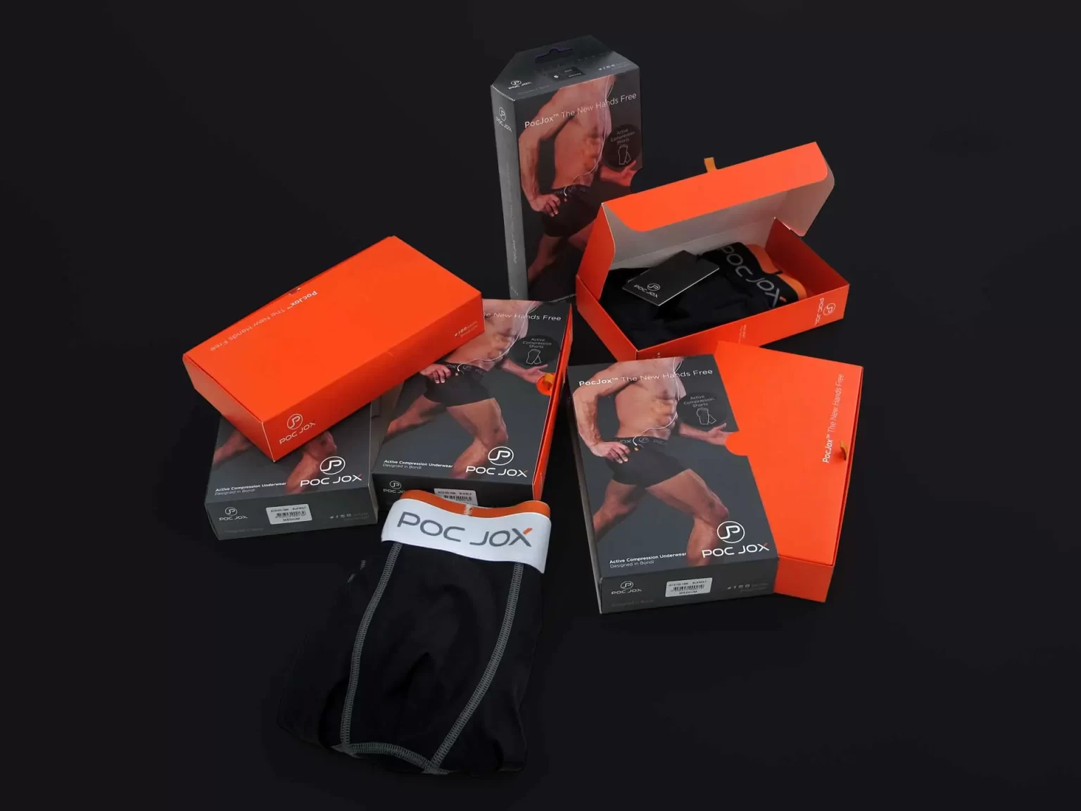 Several orange and black POC JOX packages, with some opened, revealing black activewear undergarments, are displayed against a dark background.