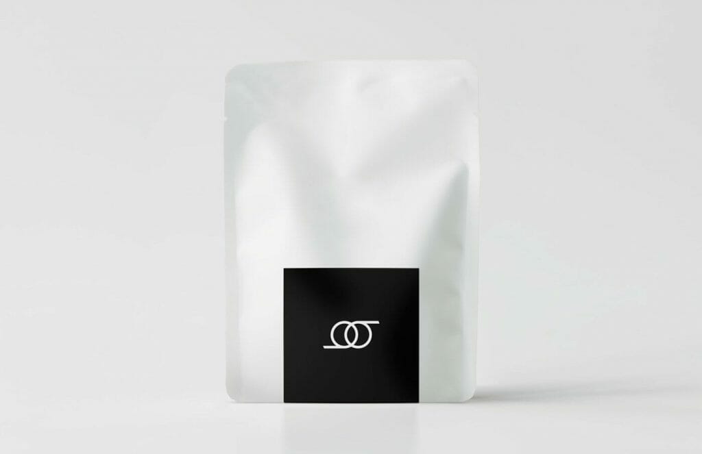 A white and black coffee bag on a white surface.