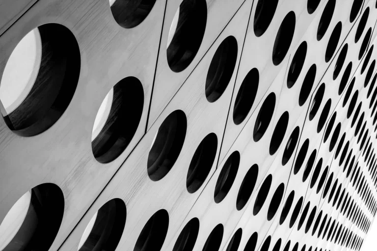Close-up of a perforated metal surface with rows of circular holes arranged in a diagonal pattern.